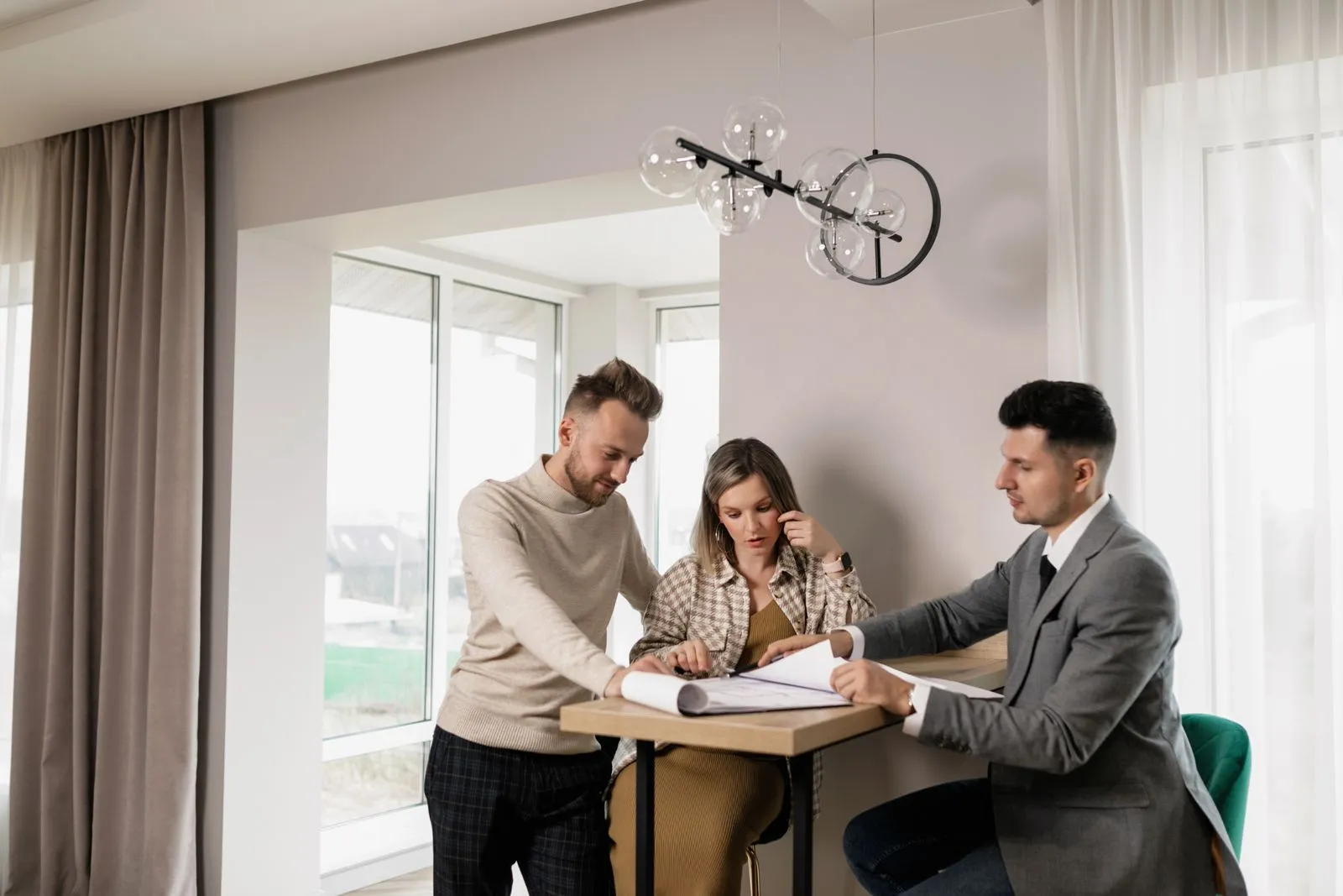 Couple assis face à un notaire, contrat et clés d'un logement sur la table